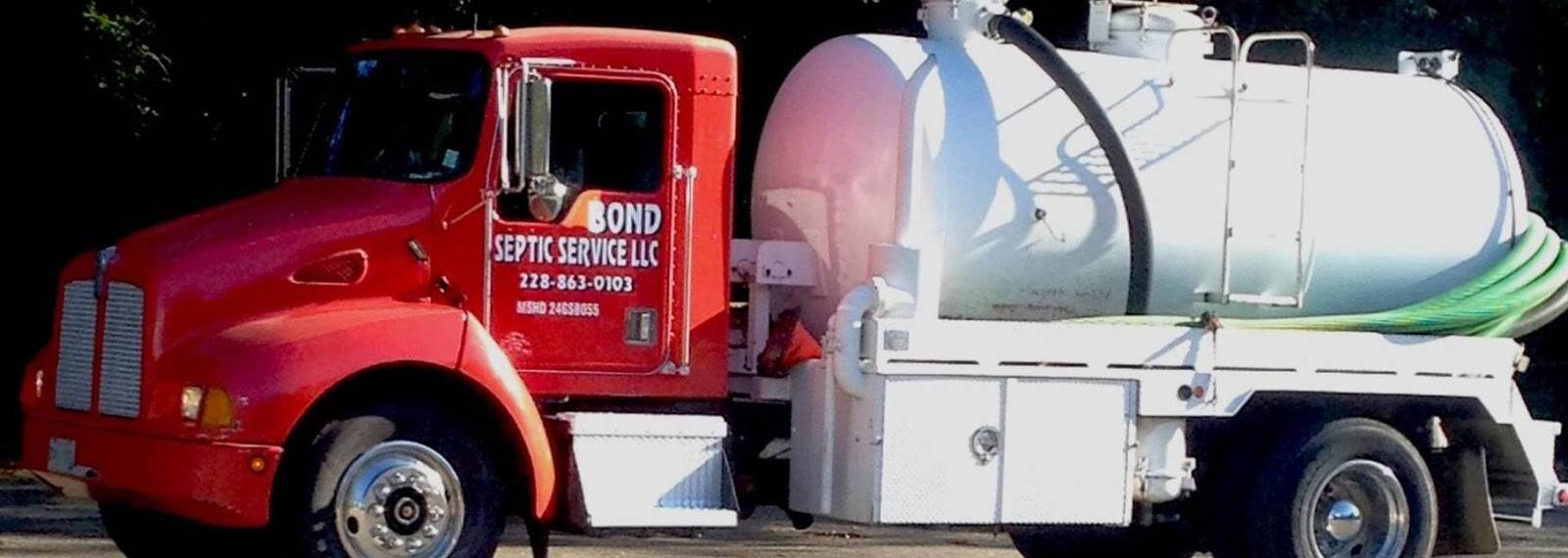 Close crop of a red truck cab and white vacuum tank, with a green suction hose coiled at the back